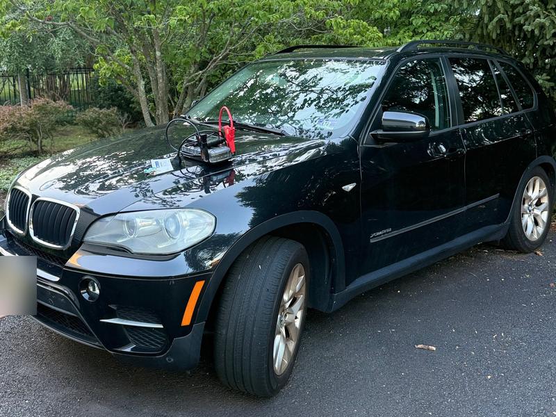 Black BMW X5 with a jump starter on the hood bought by Try Auto Way, car buyer in Princeton NJ