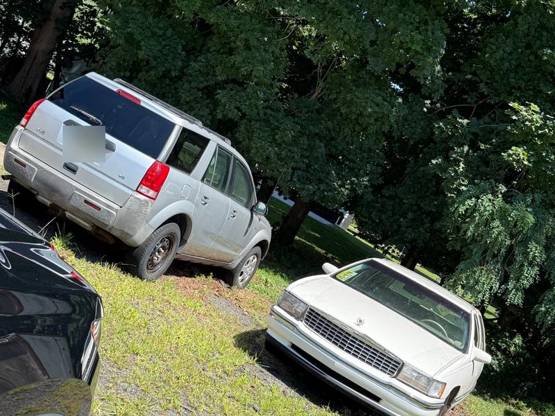 Silver Saturn Vue and white Cadillac sedan parked on grass bought by Try Auto Way, car buyer in Princeton NJ